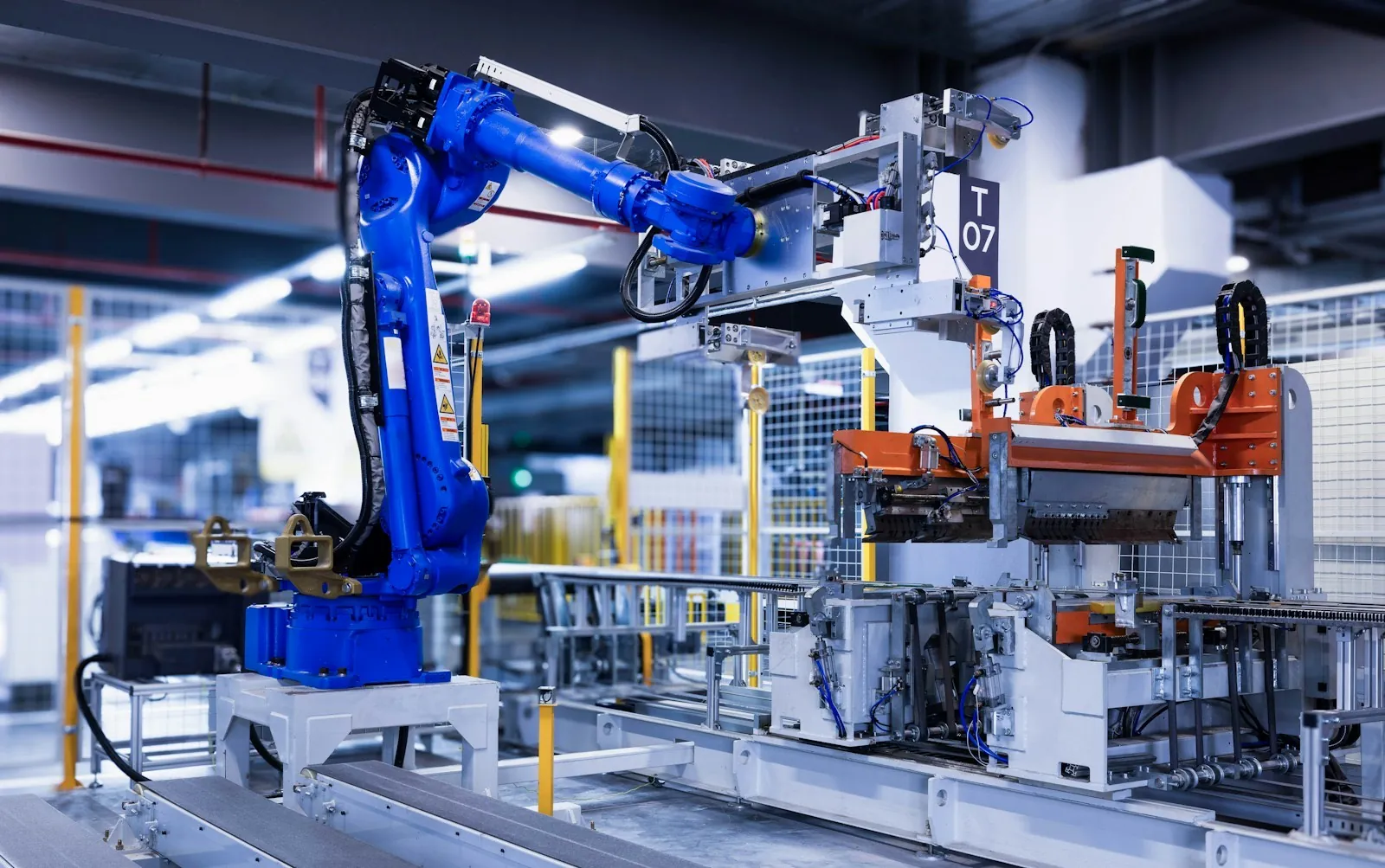 Blue industrial robot arm working alongside automated machinery in a factory cell