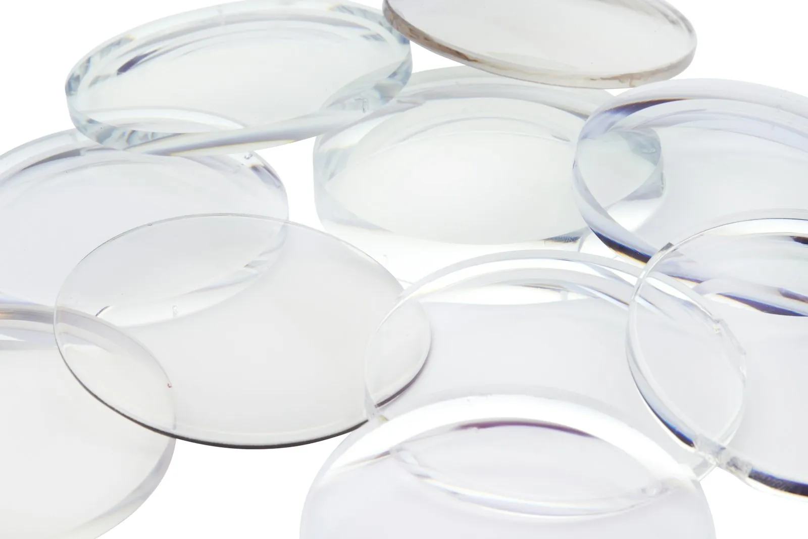 Clear uncut optical lens blanks stacked on a white surface