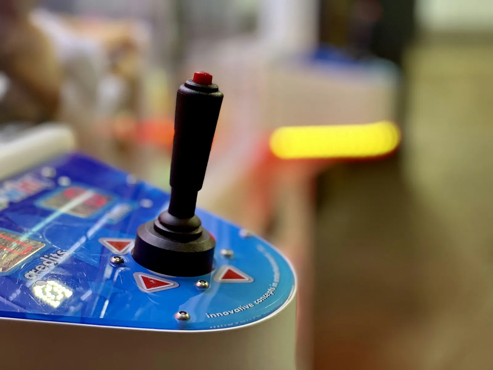 Joystick with a red top button mounted on a blue control panel