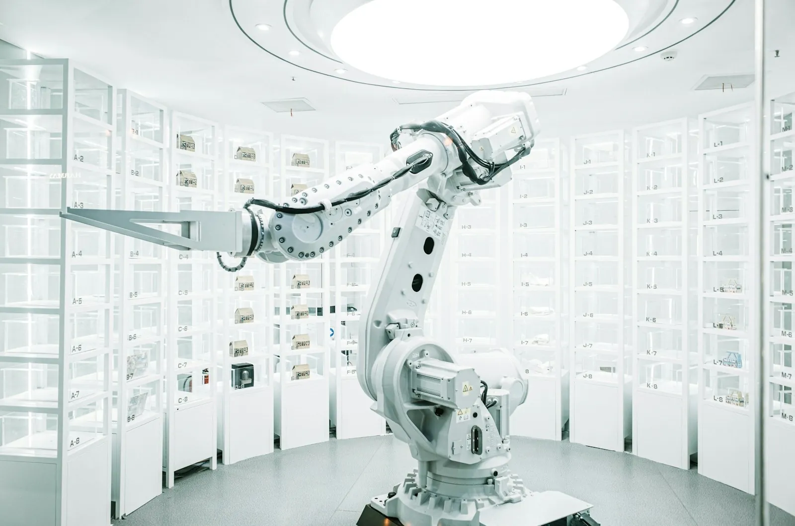 White six-axis industrial robot arm operating in a bright automated storage room